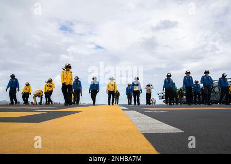 220729-N-CM110-1066 OCEANO PACIFICO (29 luglio 2022) – i marinai e i marines eseguono un depliuto di corpi estranei (FOD) sul ponte di volo a bordo della nave d'assalto anfibio USS Tripoli (LHA 7), 29 luglio 2022. Tripoli opera nell'area delle operazioni della flotta 7th degli Stati Uniti per migliorare l'interoperabilità con alleati e partner e fungere da pronta forza di risposta per difendere la pace e mantenere la stabilità nella regione dell'Indo-Pacifico. Foto Stock