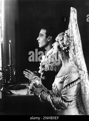 1922 , USA : l'attore del film muto RUDOLPH VALENTINO ( Rodolfo Guglielmi , 1895 - 1926 ) con LILA LEE , Still publicitary for BLOOD AND SAND ( Sangue e arena ) di Fred Niblo , dal romano di Blasco Ibanez ( 1908 ) - CINEMA MUTO - RODOLFO - atto cinematografico - LATINO LOVER - italoamericano - italo americano - italo-americano - emigrante - emigrante - italo-americano - ritratto - ritratto - torero - toreador - profilo - mantiglia - pizzo - pizzo - preghiera - preghiera - pregare - ingrassare - Brillantina - candele ---- Archivio GBB Foto Stock