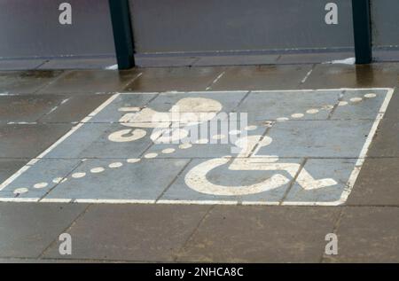 Un posto adibito a parcheggio per disabili e passeggini con bambini presso una fermata dei mezzi pubblici. Il cartello è tracciato sull'asfalto. Foto Stock