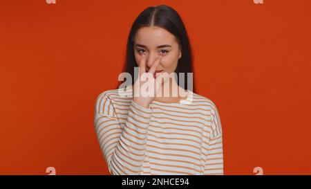 Ti sto guardando. Donna caucasica in pullover puntando i suoi occhi e la macchina fotografica, mostra che sto guardando il gesto, spiando qualcuno. Giovane adulta bella ragazza isolata da sola su sfondo rosso parete studio Foto Stock