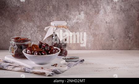 Prugne marinate con spezie in vaso di vetro sul tavolo da cucina Foto Stock