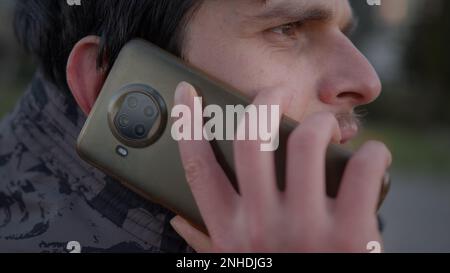 Primo piano di Young Man che parla sul cellulare all'aperto in inverno Foto Stock