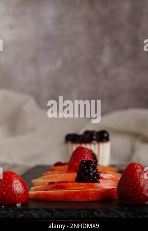 Mele rosse fresche con gocce d'acqua su una fetta di legno Foto Stock