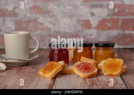 Pane tostato con marmellata e una tazza di caffè su un tavolo di legno Foto Stock