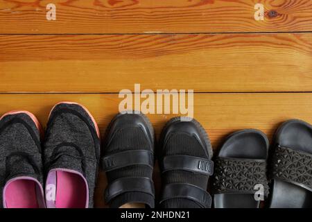 scarpe da ginnastica infradito le scarpe da ginnastica sono in fila su un pavimento di legno diverso, un sacco di scarpe da donna sul pavimento Foto Stock