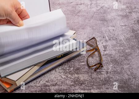 Le donne girano le pagine di un libro con uno sfondo sfocato Foto Stock