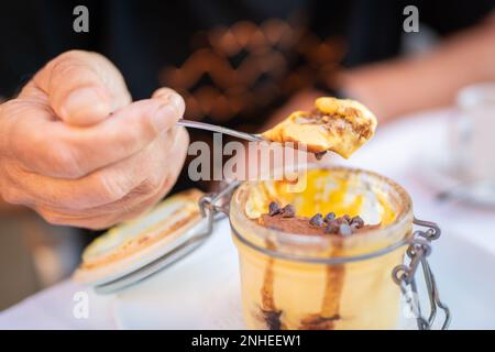 Dessert tradizionale italiano in vaso di vetro. Tiramisù su un cucchiaio. Dessert tradizionale italiano in vaso di vetro. Tiramisù su un cucchiaio. Foto Stock