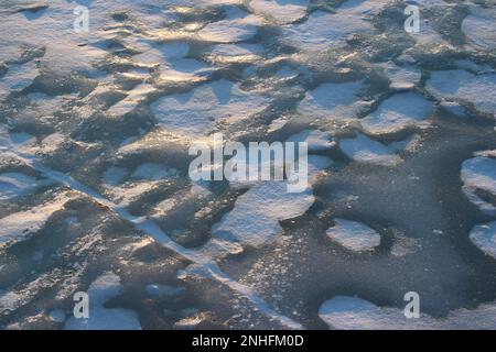 Il ghiaccio cresce sul fiume coperto di neve, sfondo ghiacciato Foto Stock