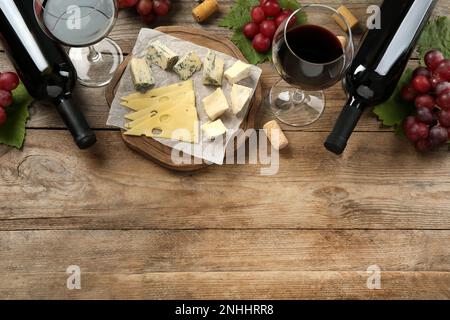 Gustoso vino rosso e spuntini su tavola di legno, piatto. Spazio per il testo Foto Stock