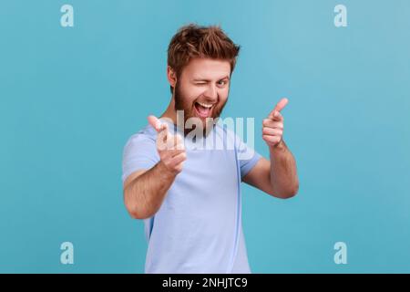 Sei speciale. Ritratto di uomo felice positivo bearded che punta le dita alla macchina fotografica e guardando con sorriso toothy, crede in voi, motivazione. Studio in interni isolato su sfondo blu. Foto Stock