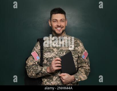 Cadet con zaino e tablet vicino alla lavagna. Educazione militare Foto Stock