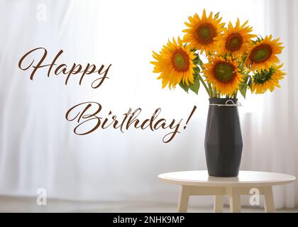 Buon compleanno! Vaso con bellissimi girasoli gialli sul tavolo in camera Foto Stock