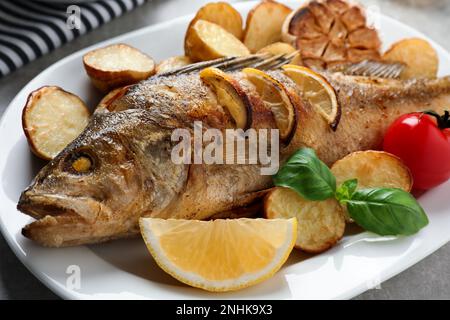 Gustoso persico arrosto fatto in casa con guarnitura sul tavolo, primo piano. Pesce di fiume Foto Stock