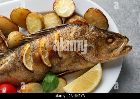 Gustoso persico arrosto fatto in casa con decorazione su tavolo grigio, primo piano. Pesce di fiume Foto Stock