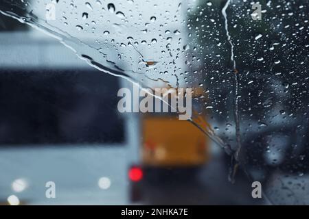 Vista sfocata della strada attraverso il parabrezza bagnato dell'auto. Tempo piovoso Foto Stock