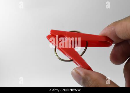 Clothespin di plastica rossa isolato su sfondo bianco. Clip in plastica Foto Stock