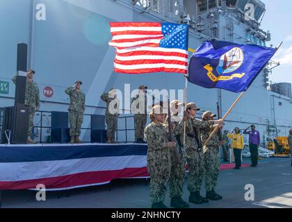 220801-N-LY160-1095 OCEANO PACIFICO (1 agosto 2022) – i membri del partito ufficiale salutano durante l'inno nazionale per una cerimonia di cambio di comando sul ponte di volo a bordo del vettore d'assalto anfibio USS Tripoli (LHA 7), 1 agosto 2022. Tripoli opera nell'area delle operazioni della flotta 7th degli Stati Uniti per migliorare l'interoperabilità con alleati e partner e fungere da pronta forza di risposta per difendere la pace e mantenere la stabilità nella regione dell'Indo-Pacifico. Foto Stock