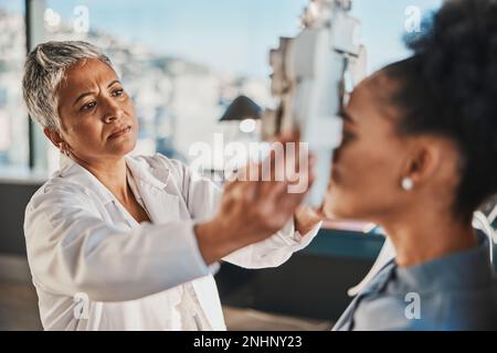 Donna anziana optometristo, paziente esame oculare e obiettivo medico in ospedale, sala di consulenza e ufficio con aiuto. Ottico anziano, esame della vista e. Foto Stock