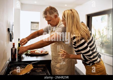 Non essere così salato, babe. una coppia matura felice che si tiene azienda nella cucina. Foto Stock