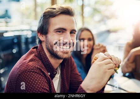 Non vedo l'ora di questo panino tutto il giorno. Ritratto corto di un bel giovane uomo d'affari che si gode il suo panino mentre fa colazione Foto Stock