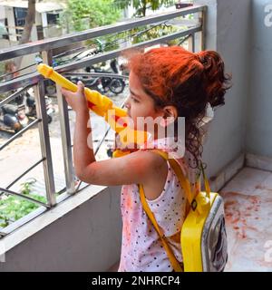 Dolce bambina indiana giocare i colori sul festival Holi, tenendo pichakaree piena di colori, festa Holi celebrazioni a Delhi, India Foto Stock