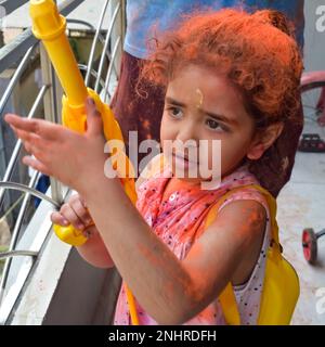 Dolce bambina indiana giocare i colori sul festival Holi, tenendo pichakaree piena di colori, festa Holi celebrazioni a Delhi, India Foto Stock