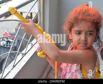 Dolce bambina indiana giocare i colori sul festival Holi, tenendo pichakaree piena di colori, festa Holi celebrazioni a Delhi, India Foto Stock