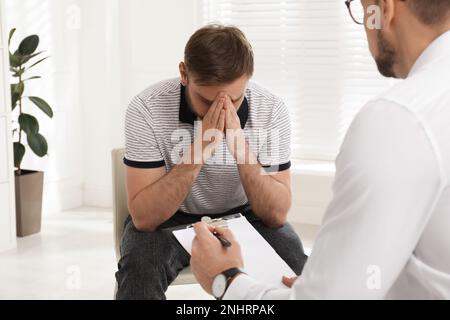 Psicoterapeuta che lavora con un giovane tossicodipendente al chiuso Foto Stock