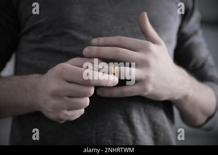 Uomo che tacca l'anello di nozze, primo piano. Truffa e rottura Foto Stock