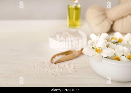 Mortaio con bellissimi fiori di gelsomino e pestello su tavola di legno bianco, primo piano. Spazio per il testo Foto Stock