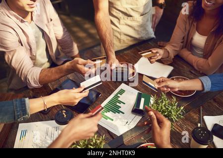 Con quel bonus, erano tutti disposti a pagare. Immagine ad angolo alto di un gruppo irriconoscibile di colleghi che tengono fuori le loro carte bancarie per pagare la fattura a A. Foto Stock