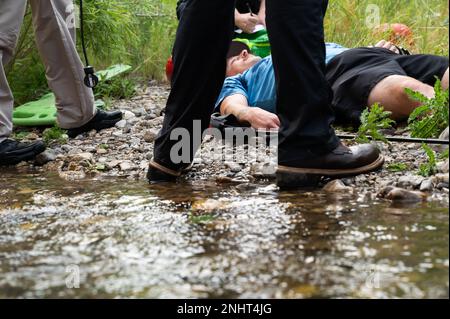 Senior Airman Rocky Lane, 341st Civil Engineer Squadron, operatore di attrezzature pesanti, si posa a terra accanto a Belt Creek per simulare un infortunio durante un'escursione il 2 agosto 2022, in Sluice Boxes state Park, Month. Lane stava giocando in un esercizio di ricerca e salvataggio in cui il 40th Elicottero Squadron, 341st CES Fire Department e 341st Medical Group hanno lavorato insieme per trovare Lane, fornire la triage iniziale e il trattamento delle sue lesioni simulate e evacuarlo dalla scena per ulteriore cura. Foto Stock