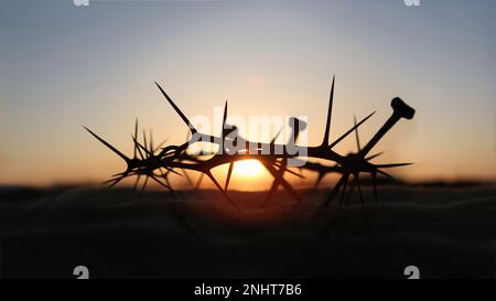 La croce, la corona di spine, le unghie e il tramonto rosso simboleggiano il sacrificio e la sofferenza di Gesù Cristo, la settimana della Passione e il concetto di Quaresima Foto Stock