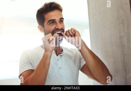 Arrivare in luoghi difficili da raggiungere. un bel giovanotto che gli galleggiava i denti mentre guardava il suo riflesso nello specchio di casa. Foto Stock