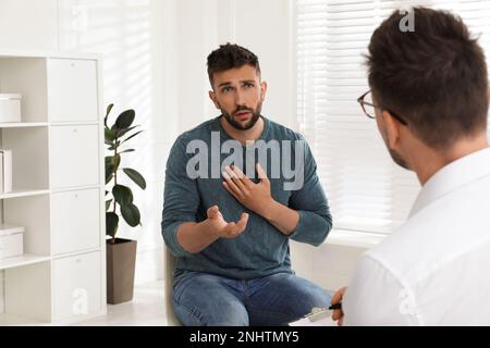 Psicoterapeuta che lavora con l'uomo tossicodipendente al chiuso Foto Stock