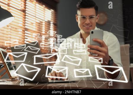 Uomo d'affari che invia e-mail al tavolo al chiuso, fuoco a portata di mano Foto Stock