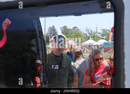 Petty Officer 1st Class Matt Duran, un tecnico elettrico dell'avionica presso Air Station Traverse City, guida i bambini in un tour di uno degli elicotteri MH-60T Jayhawk al 2 agosto 2022. I tour hanno fatto parte della celebrazione della Giornata dei bambini del 2022. STATI UNITI Guardia costiera foto di Rin Concordia. Foto Stock