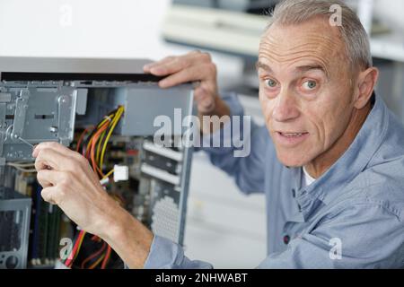 uomo anziano che assembla un computer desktop Foto Stock