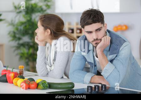 coppia divisa con braccia incrociate in cucina Foto Stock