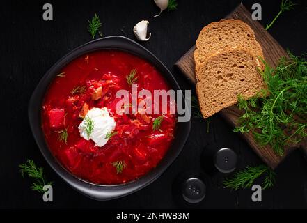 Borscht ucraino tradizionale. Ciotola di borsch di barbabietola rossa con crema bianca. Radice di barbabietola deliziosa zuppa. Cibo ucraino. Vista dall'alto, dall'alto Foto Stock