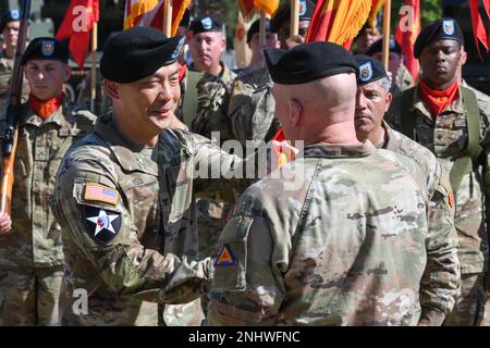 STATI UNITI Wilbur Hsu, a sinistra, comandante entrante della Brigata di artiglieria di campo 41st, accetta i colori unitari dal Brig Gen. Joseph Hilbert, comandante Generale del comando di addestramento dell'esercito 7th (7ATC) durante una cerimonia di Cambio di comando presso la 7ATC's Grafenwoehr Training Area, Germania, 3 agosto 2022. Il col. Daniel Miller cede il comando al col. Wilbur Hsu. Foto Stock