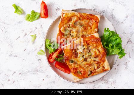 Mini pizza per bambini, piccole torte aperte con prosciutto, salsa di pomodoro, mozzarella e formaggio in cestino su sfondo chiaro. Vista dall'alto Foto Stock