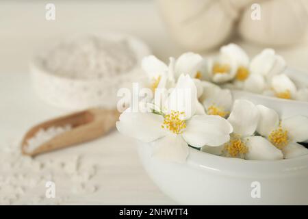 Mortaio con bellissimi fiori di gelsomino e pestello su tavola bianca, primo piano. Spazio per il testo Foto Stock