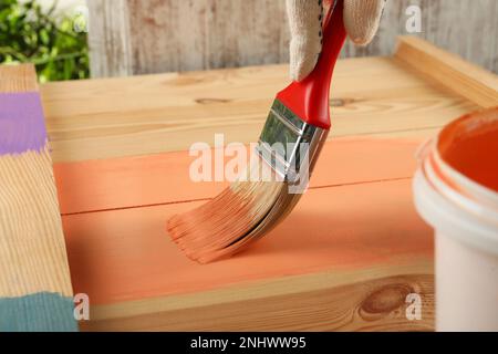 Lavoratore che applica vernice di corallo su superficie di legno, primo piano Foto Stock