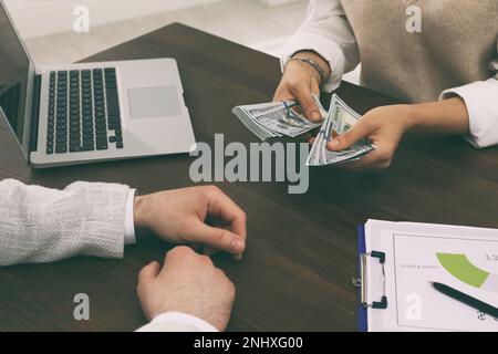 Cassiere che dà denaro a un uomo d'affari alla scrivania in banca, primo piano Foto Stock