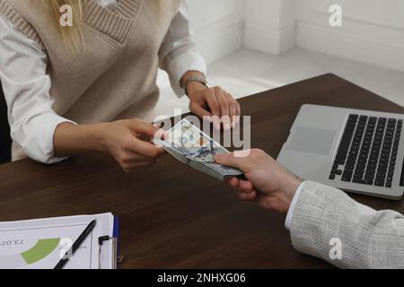 Cassiere che dà denaro a un uomo d'affari alla scrivania in banca, primo piano Foto Stock