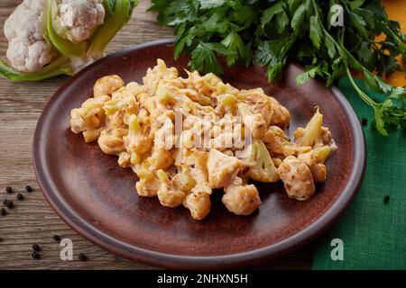 cavolfiore arrosto con spezie ed erbe, tovagliolo giallo e verde, su fondo in legno Foto Stock