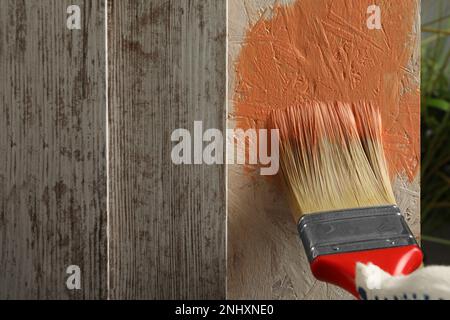 Lavoratore che applica vernice di corallo su superficie di legno, primo piano. Spazio per il testo Foto Stock