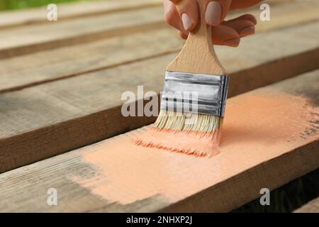 Donna che dipinge la superficie di legno con colorante corallo, primo piano Foto Stock