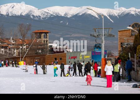 Bansko, Bulgaria - 11 febbraio 2023: Panorama della stazione sciistica invernale bulgara con cabine di cabinovia, vista sulle cime delle montagne e pista con non sciatori Foto Stock